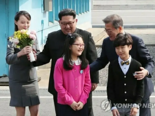 金委員長が韓国の子どもたちから受け取った歓迎の花束を妹の与正氏に渡している＝２７日、板門店（聯合ニュース）