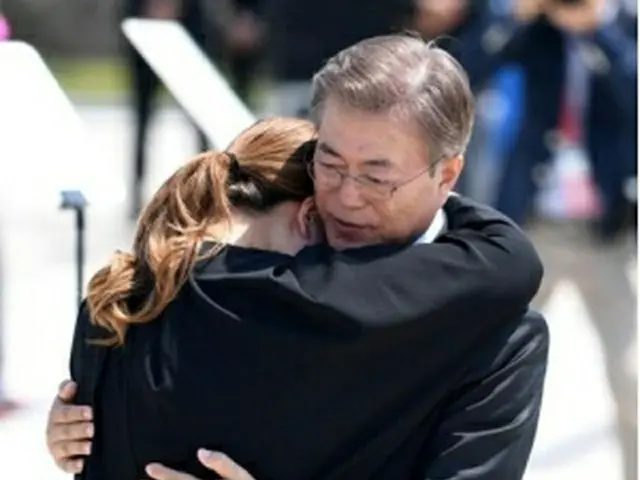 昨年の記念式典で、民主化運動で命を落とした犠牲者の遺族と抱き合う文在寅大統領＝（聯合ニュース）