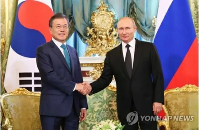 会談で握手を交わす文大統領（左）とプーチン大統領＝２２日、モスクワ（聯合ニュース）