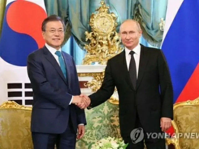 会談で握手を交わす文大統領（左）とプーチン大統領＝２２日、モスクワ（聯合ニュース）