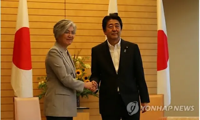 握手を交わす康長官（左）と安倍首相＝８日、東京（聯合ニュース）