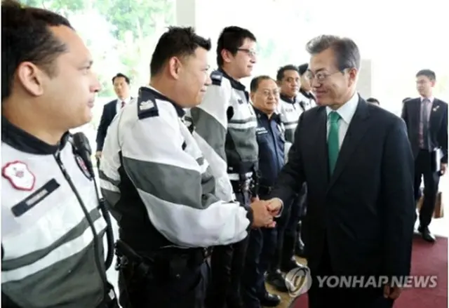 空港で現地の警察官らとあいさつする文大統領＝１３日、ソウル（聯合ニュース）