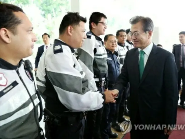 空港で現地の警察官らとあいさつする文大統領＝１３日、ソウル（聯合ニュース）