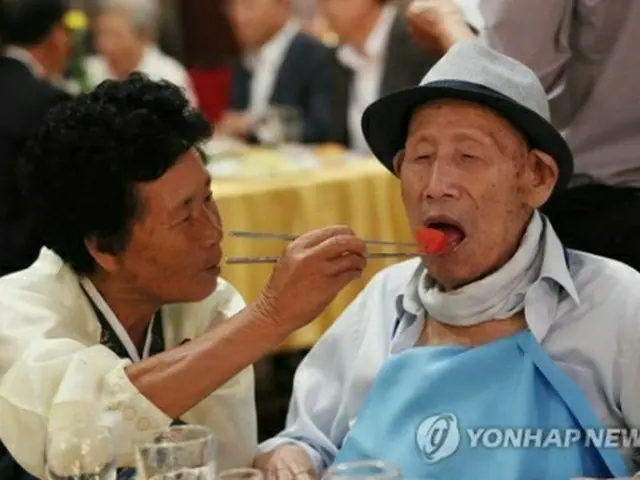 ２０日の夕食会で、北朝鮮に住む娘（７０）が韓国の父親（１００）に料理を食べさせている＝（聯合ニュース）