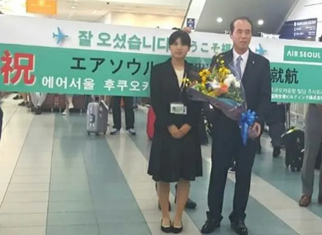 福岡空港ビルディング関係者より、エアソウル代表取締役社長チョ・ギュヨン氏へ花束を贈呈。（オフィシャル）
