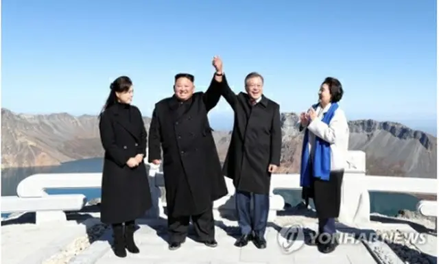 握った手を掲げて記念撮影する文大統領（右から2人目）夫妻と金委員長（左から2人目）夫妻（写真共同取材団）＝20日、白頭山（聯合ニュース）