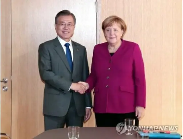会談で握手を交わす文大統領（左）とメルケル首相＝１９日、ブリュッセル（聯合ニュース）