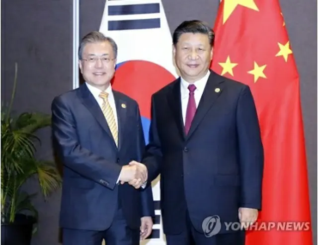 握手を交わす文大統領（左）と習主席＝１７日、パプアニューギニア（聯合ニュース）