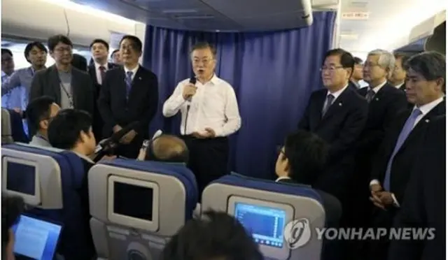 空軍１号機で記者団の質問に応じる文大統領＝１日、空軍１号機（聯合ニュース）
