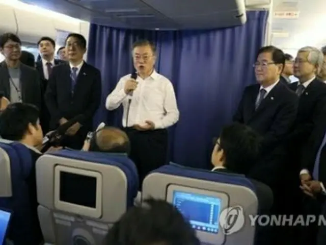 空軍１号機で記者団の質問に応じる文大統領＝１日、空軍１号機（聯合ニュース）