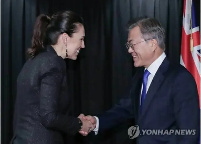 握手を交わす文大統領（右）とアーダーン首相＝4日、オークランド（聯合ニュース）