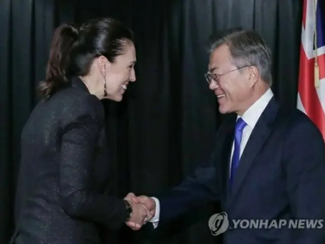 握手を交わす文大統領（右）とアーダーン首相＝4日、オークランド（聯合ニュース）