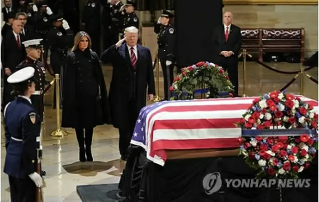 ワシントンの議会議事堂に安置されたブッシュ氏のひつぎの前で敬礼するトランプ米大統領＝３日、ワシントン（ＡＰ＝聯合ニュース）