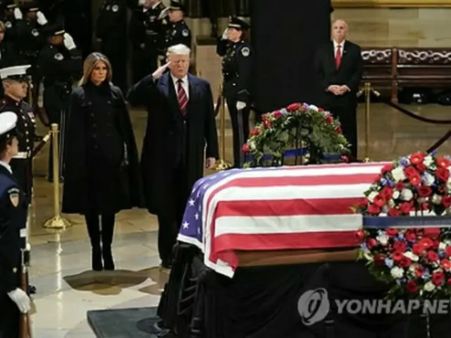 ワシントンの議会議事堂に安置されたブッシュ氏のひつぎの前で敬礼するトランプ米大統領＝３日、ワシントン（ＡＰ＝聯合ニュース）
