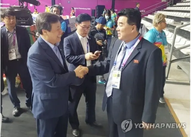 昨夏のジャカルタ・アジア大会で握手する韓国の都鍾煥・文化体育観光部長官（左）と北朝鮮の金日国体育相
