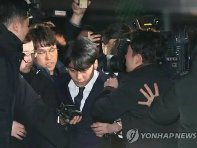 報道陣が取り囲む中、警察での取り調べを終えて帰宅するV．Iさん＝15日、ソウル（聯合ニュース）
