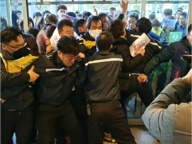 市庁舎の入り口で衝突する団体のメンバーと市庁関係者＝15日、釜山（聯合ニュース）