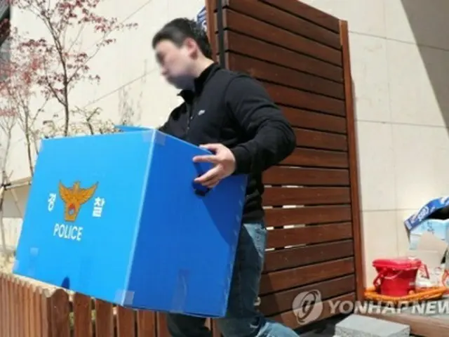 家宅捜索で押収品を運び出す警察関係者＝１６日、河南（聯合ニュース）