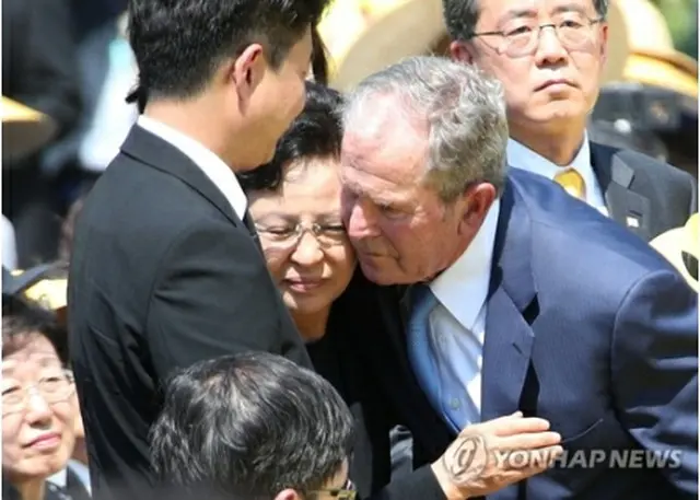 追悼式で権良淑夫人（中央）を抱き寄せるブッシュ元米大統領＝２３日、金海（聯合ニュース）