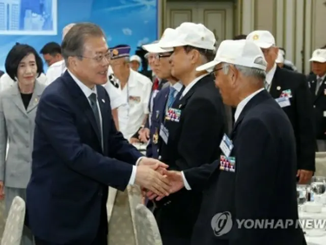昼食会で出席者と握手を交わす文大統領（左）＝24日、ソウル（聯合ニュース）