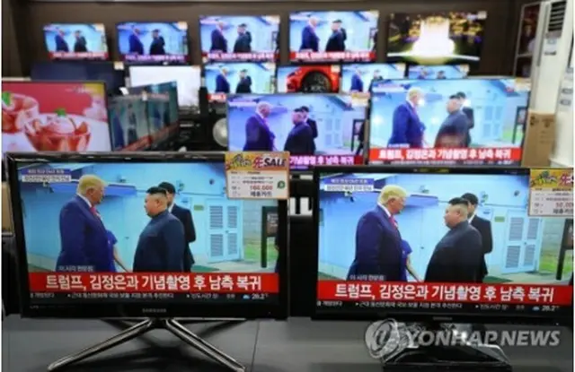 板門店で会話するトランプ氏と金正恩氏を映すテレビモニター＝３０日、ソウル（聯合ニュース）