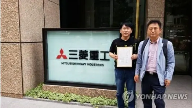 6月21日、三菱重工業の本社前で同社側に渡す交渉要請書を見せる原告代理人ら＝（聯合ニュース）