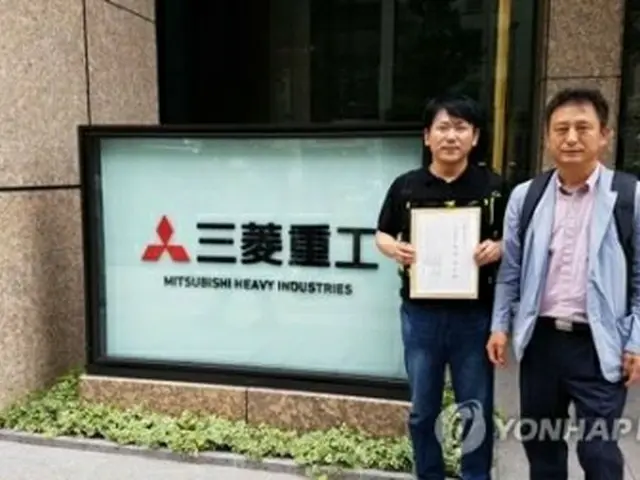6月21日、三菱重工業の本社前で同社側に渡す交渉要請書を見せる原告代理人ら＝（聯合ニュース）