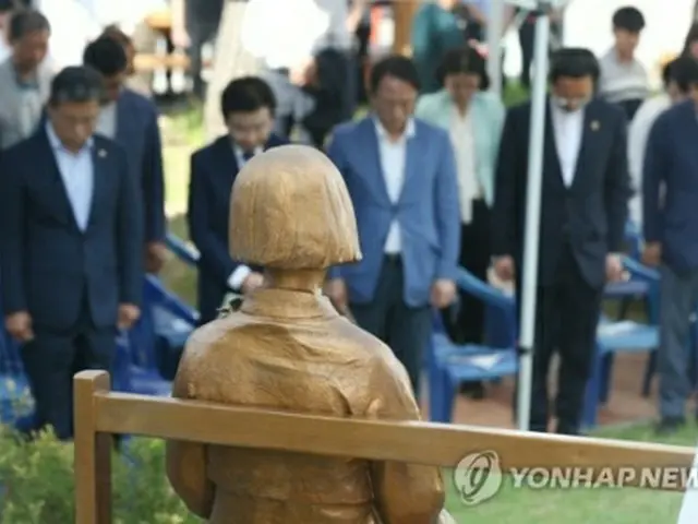 光州で開かれた記念行事で、少女像の前で黙とうする参加者ら＝１４日、光州（聯合ニュース）