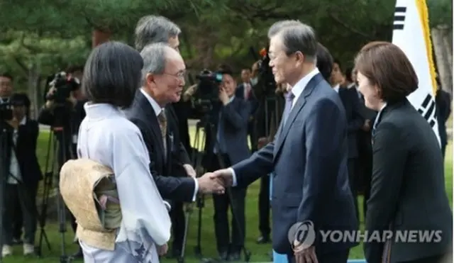 握手を交わす文大統領（右）と長嶺氏＝１８日、ソウル（聯合ニュース）