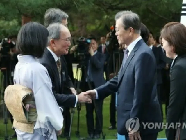 握手を交わす文大統領（右）と長嶺氏＝１８日、ソウル（聯合ニュース）