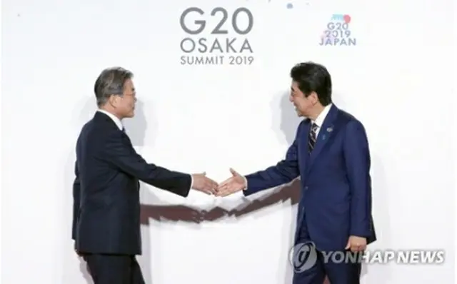 ６月２８日に大阪で開かれた主要２０カ国・地域（Ｇ２０）首脳会議で握手を交わす文大統領（左）と安倍首相＝（聯合ニュース）