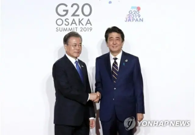 ６月に大阪で開かれた主要２０カ国・地域首脳会議（Ｇ２０サミット）で握手する文大統領（左）と安倍首相＝（聯合ニュース）
