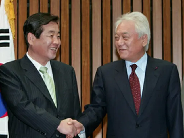 交渉前に握手を交わす中道改革統合新党の金ハンギル代表（右）と民主党の朴相千代表＝21日、ソウル（聯合）