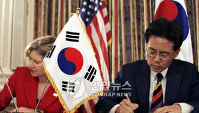 協定文に署名する金鉉宗通商交渉本部長とシュワブ米通商代表部代表＝30日、ワシントン（聯合）