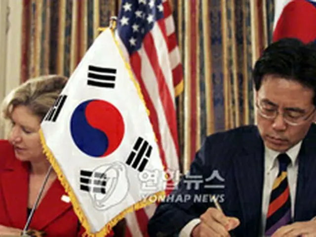 協定文に署名する金鉉宗通商交渉本部長とシュワブ米通商代表部代表＝30日、ワシントン（聯合）