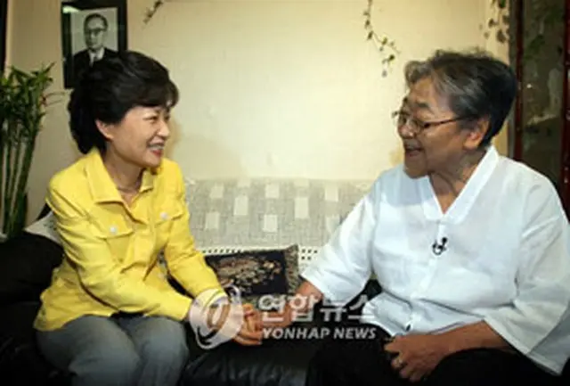 キム・ヒスクさんの手を取り会話する朴槿恵前代表＝11日、ソウル（聯合）