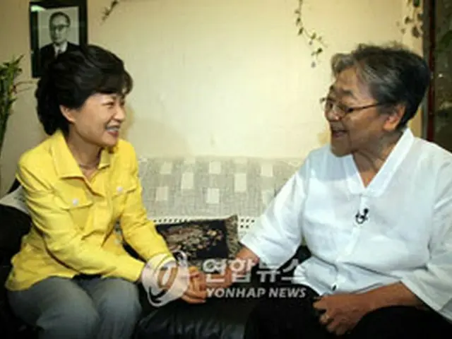 キム・ヒスクさんの手を取り会話する朴槿恵前代表=11日、ソウル(聯合)