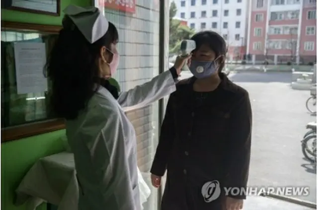 北朝鮮・平壌市内の病院の入り口で、看護師が来院者の体温を確認している＝（AFP＝聯合ニュース）