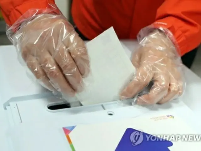 期日前投票所で、有権者が新型コロナウイルス感染の拡大防止策として使い捨て手袋をつけて投票している＝１０日、釜山（聯合ニュース）