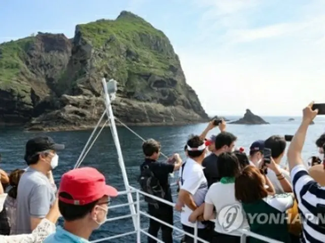 独島を撮影する旅客船の乗客＝１３日、独島（聯合ニュース）