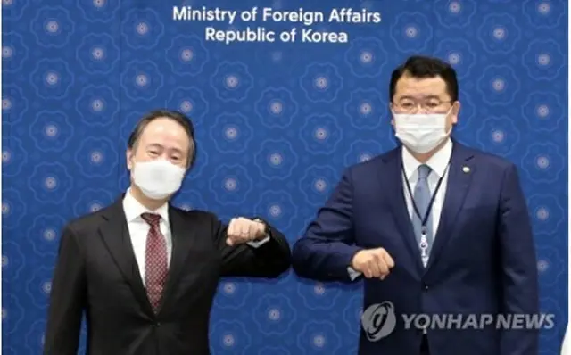 肘を合わせてあいさつする崔氏（右）と冨田氏＝7日、ソウル（聯合ニュース）