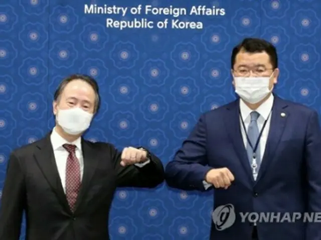 肘を合わせてあいさつする崔氏（右）と冨田氏＝7日、ソウル（聯合ニュース）