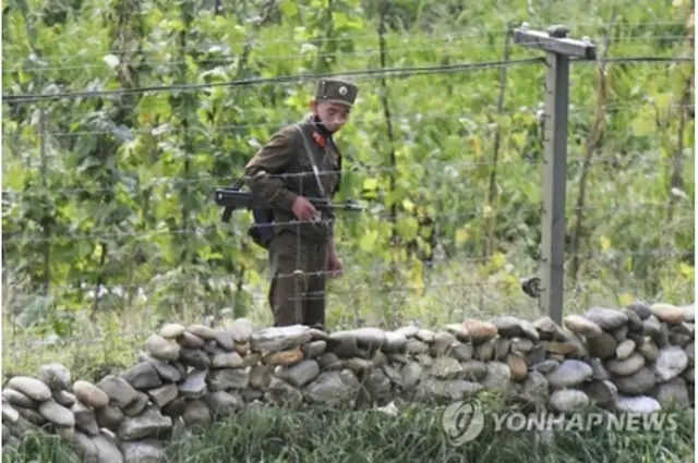今月初め、中国・吉林省長白朝鮮族自治県から撮影した北朝鮮側。銃を持った朝鮮人民軍の兵士が鴨緑江沿いを警備している（資料写真）＝（共同＝聯合ニュース）
