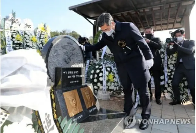 追悼式に先立ち、犠牲者の墓碑に手を置く徐長官＝（聯合ニュース）