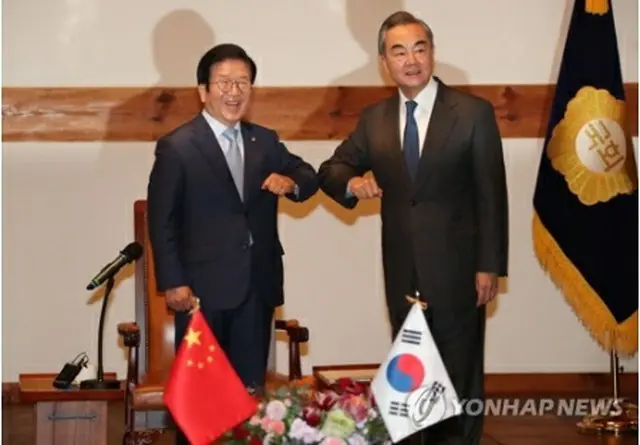 ひじを合わせてあいさつする朴炳錫氏（左）と王毅氏＝27日、ソウル（聯合ニュース）