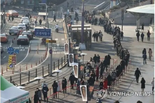 ソウル駅広場に設けられた新型コロナウイルスの臨時検査所を訪れた市民が、列を作って順番を待っている=21日、ソウル（聯合ニュース）