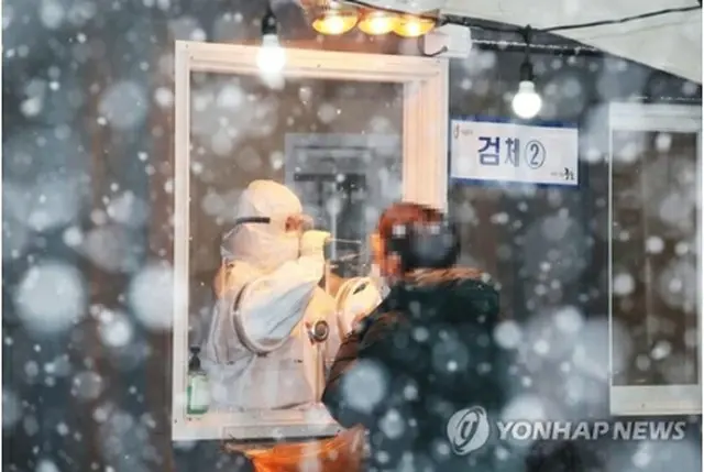 雪が降りしきる中、ソウル駅前の広場の臨時検査所で新型コロナウイルスの検査を受ける市民＝１２日、ソウル（聯合ニュース）