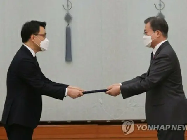 金氏（左）に任命状を手渡す文大統領＝21日、ソウル（聯合ニュース）