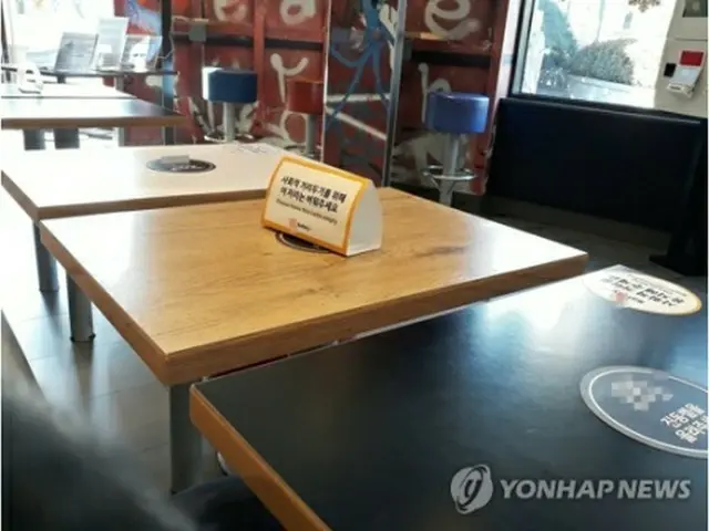 カフェのテーブルに社会的距離の確保を呼びかける案内が置かれている（資料写真）＝（聯合ニュース）