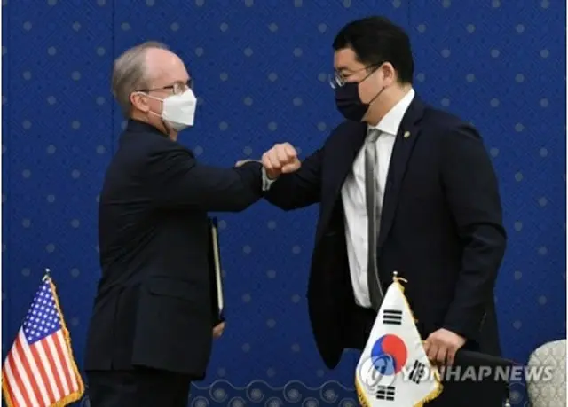 署名を終え、ひじを突き合わせてあいさつする崔鍾建氏（右）とラプソン氏＝８日、ソウル（聯合ニュース）